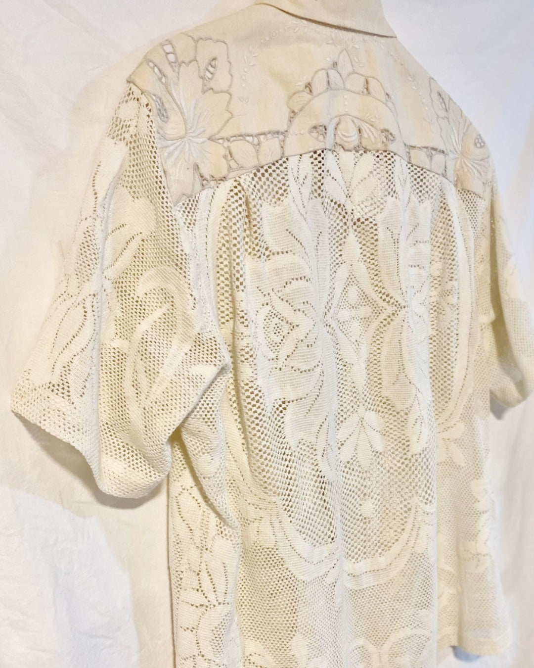 The Ivory shirt is an individually handcrafted unisex piece. It is made from a vintage machine knitted (stretch) cotton lace table cloth and is teamed with a linen embroidered supper cloth for the collar and back yoke